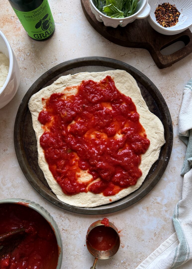 pizza crust with crushed tomatoes before baking