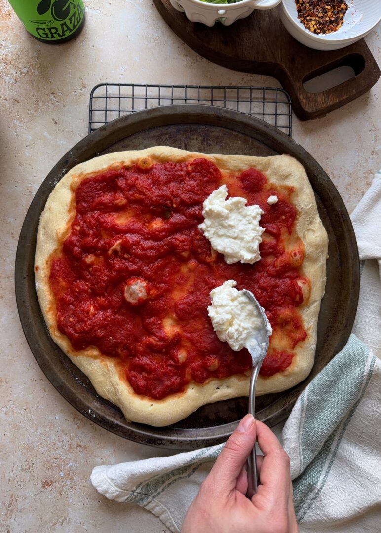 scooping stracciatella on margherita pizza