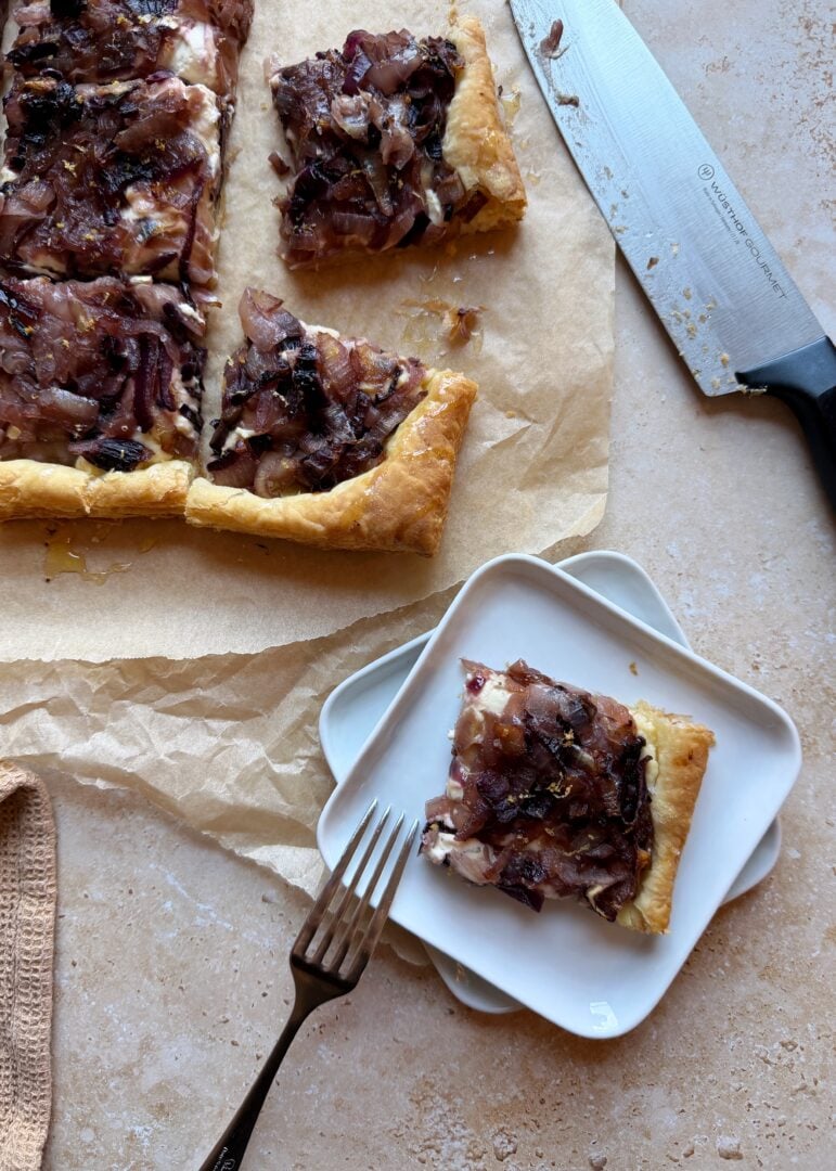 serving of caramelized onion and boursin tart on white plate