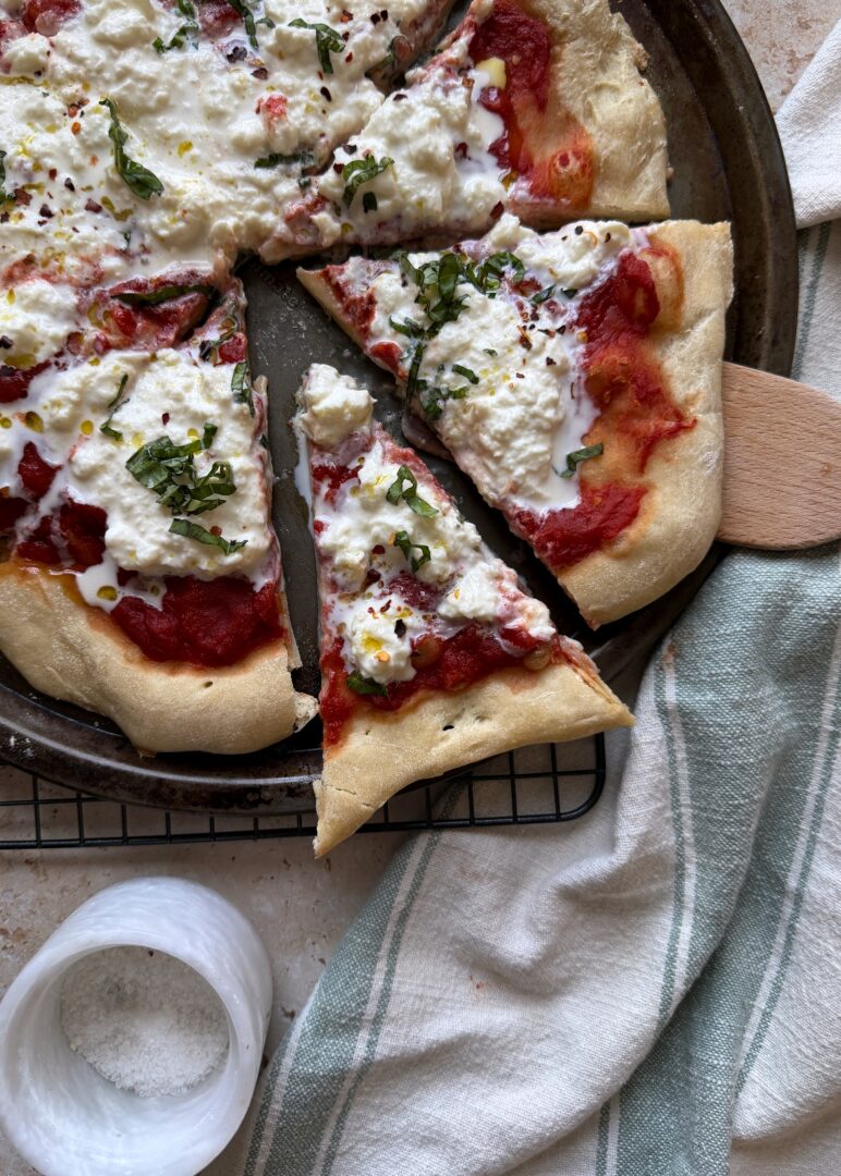 slice of stracciatella pizza with fresh basil