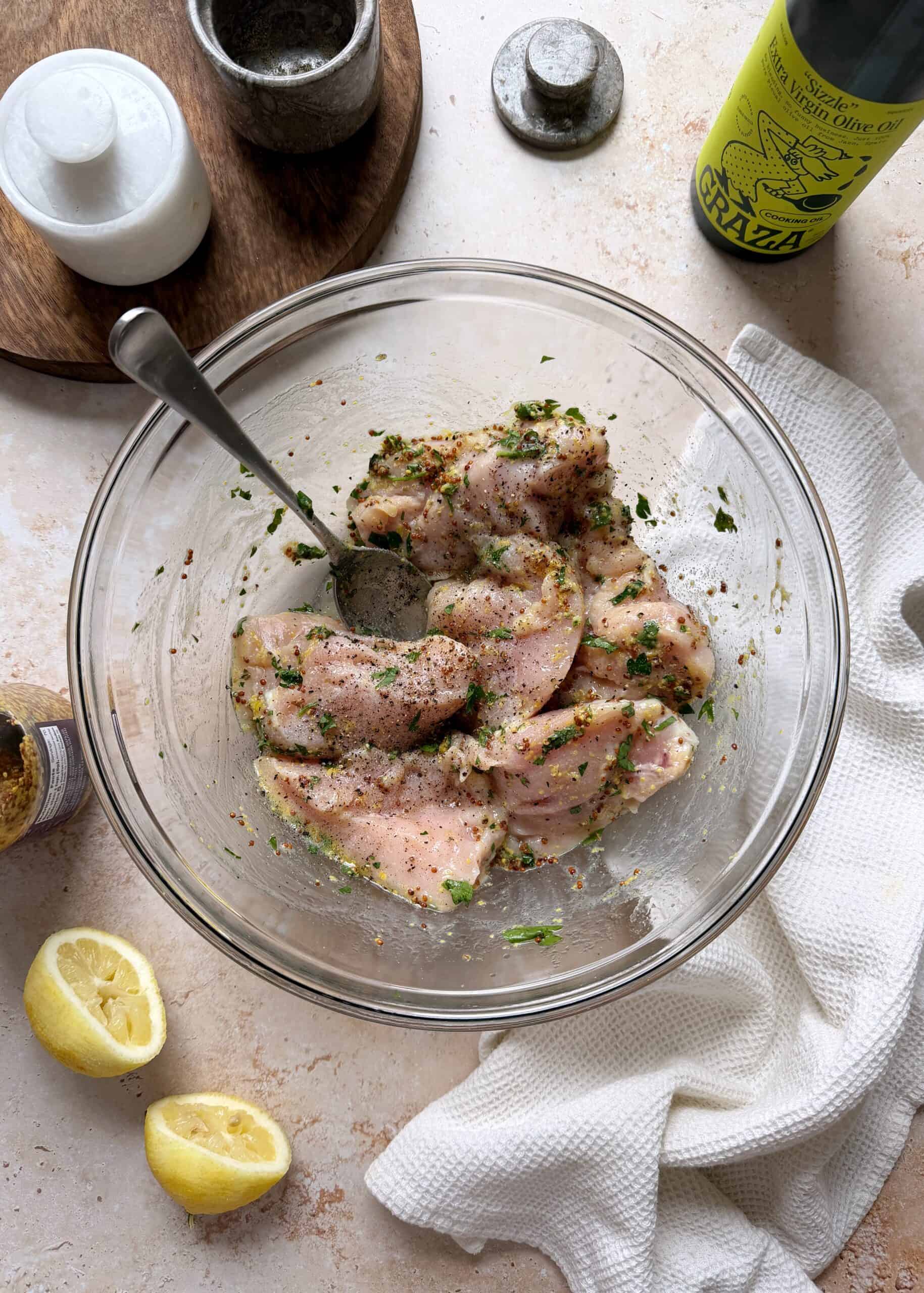 mediterranean chicken marinating in a glass bowl