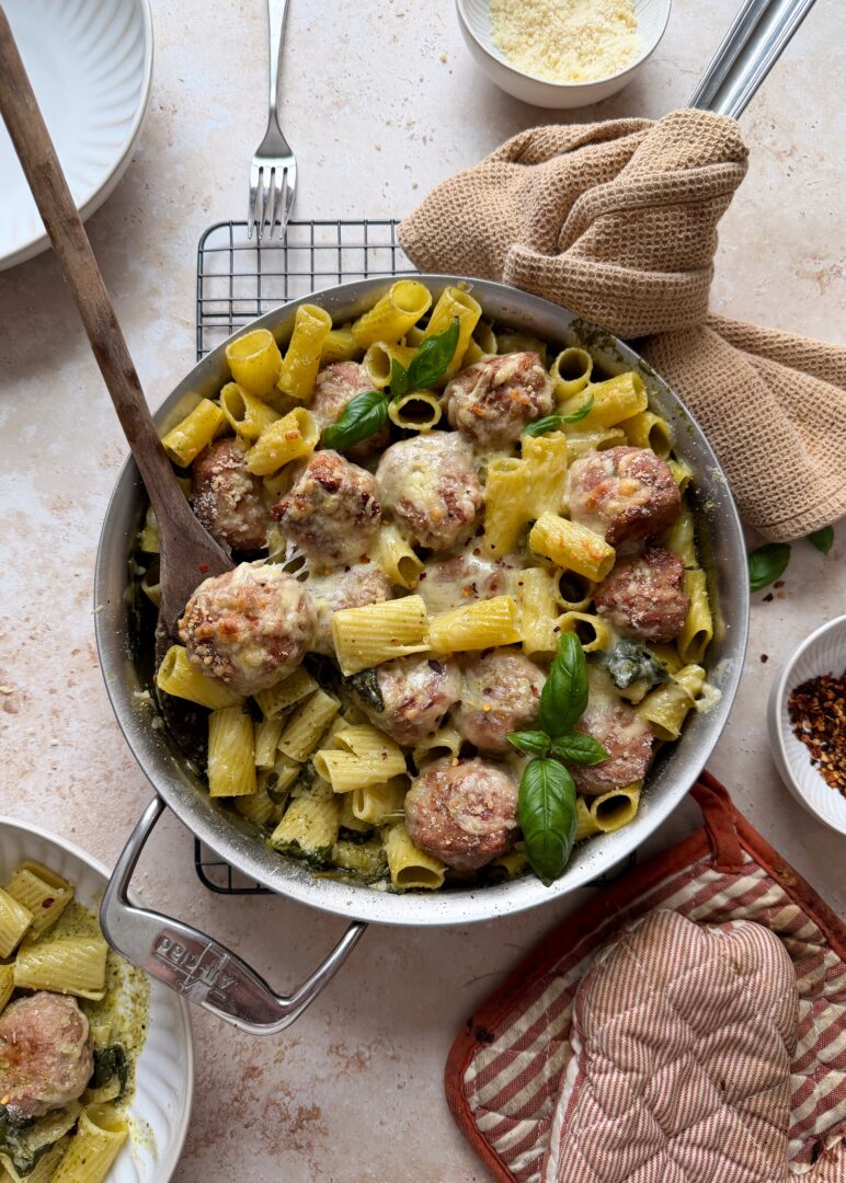 saute pan with cheesy pesto turkey meatballs and rigatoni with bowl on the side