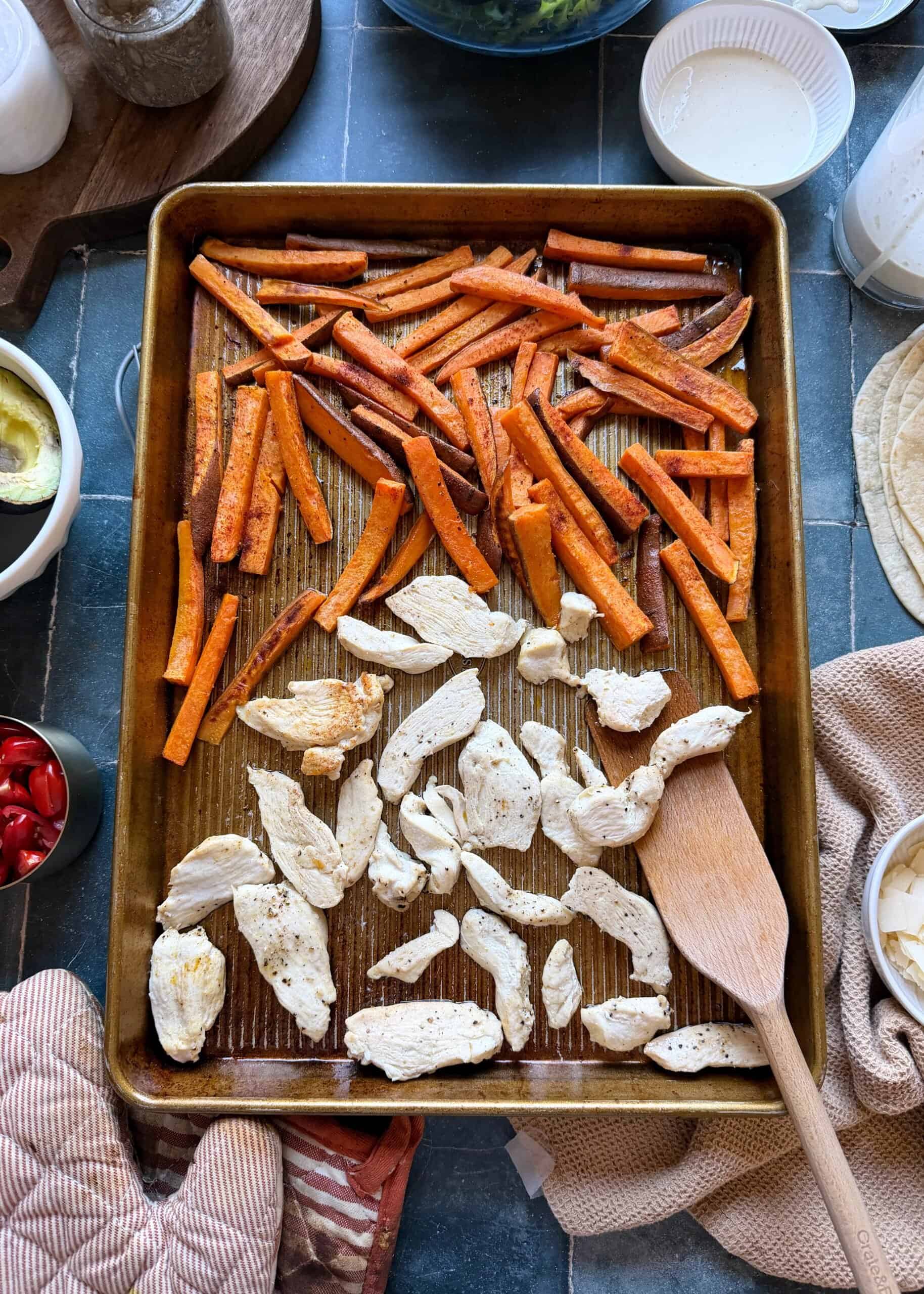 sliced chicken and sweet potatoes fries baked on a baking sheet