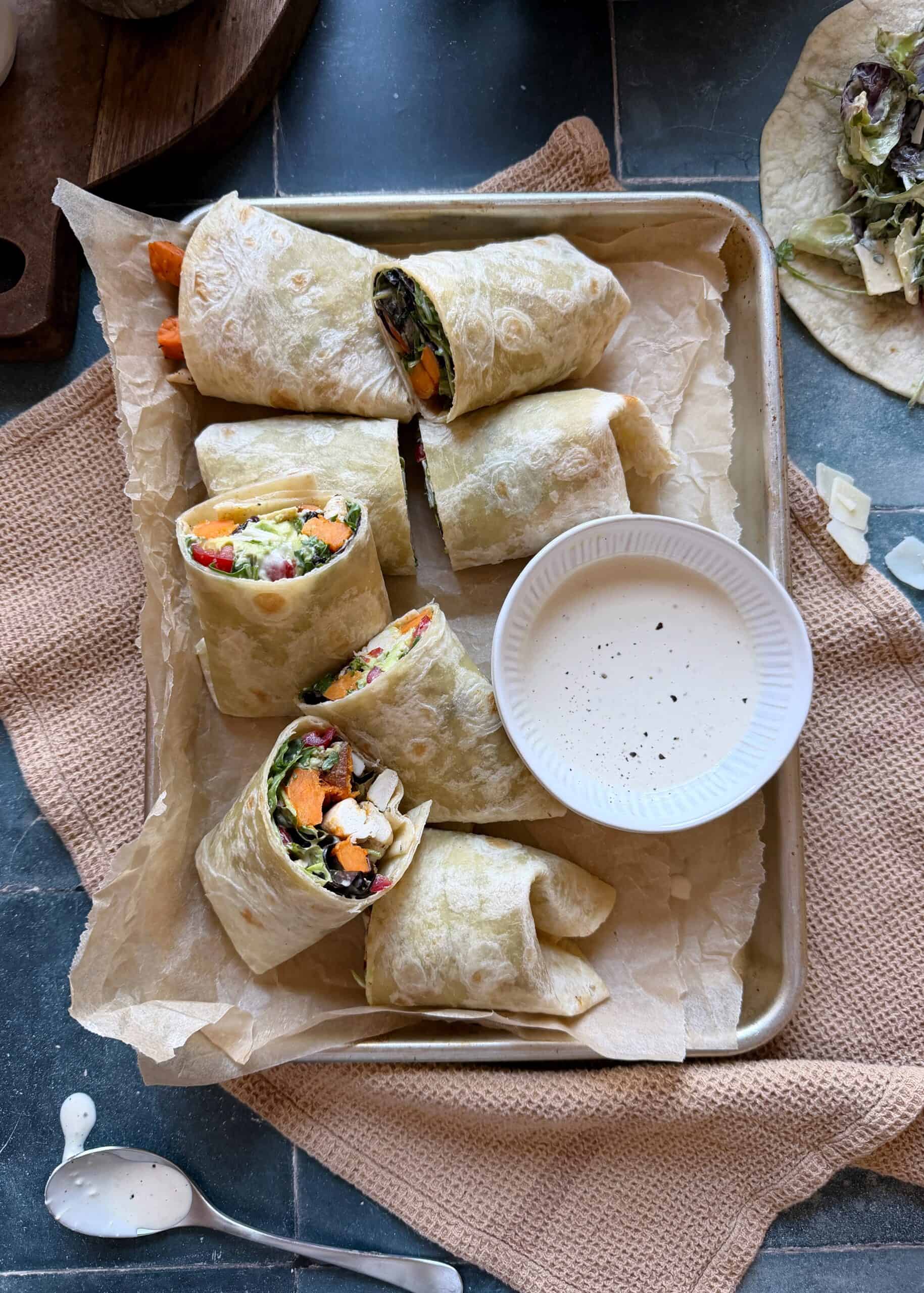 tray of chicken caesar wrap with sweet potato and extra dressing in a bowl