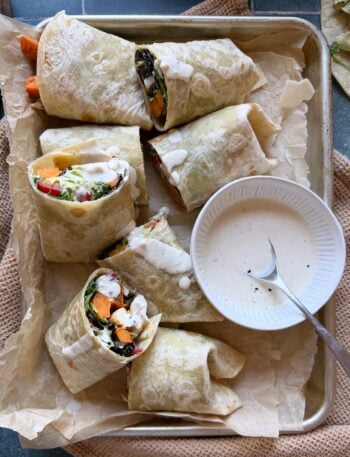 trayful of halved chicken caesar wraps with sweet potato fries with extra dressing