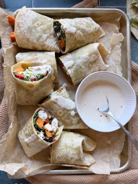 trayful of halved chicken caesar wraps with sweet potato fries with extra dressing