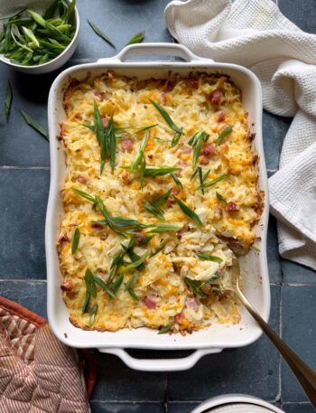 ham and cheese hash brown casserole with a gold serving spoon