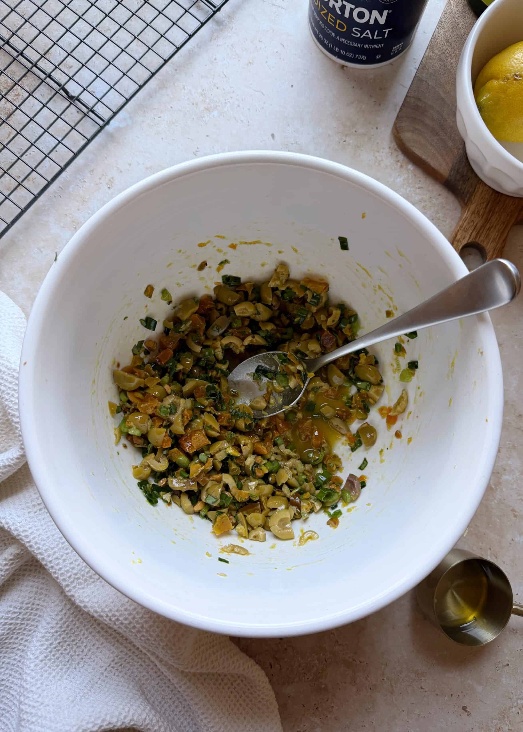 olive apricot and pistachio salad in a white mixing bowl