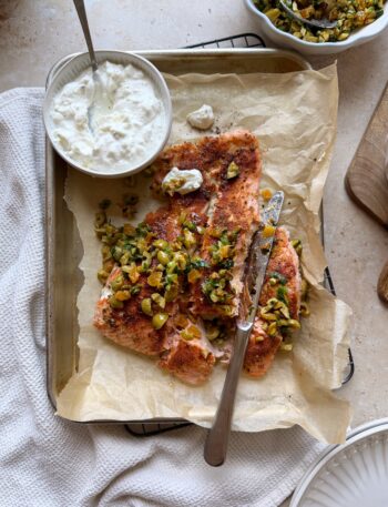 roasted salmon with olive and apricot salad on a baking sheet with feta yogurt sauce on the side