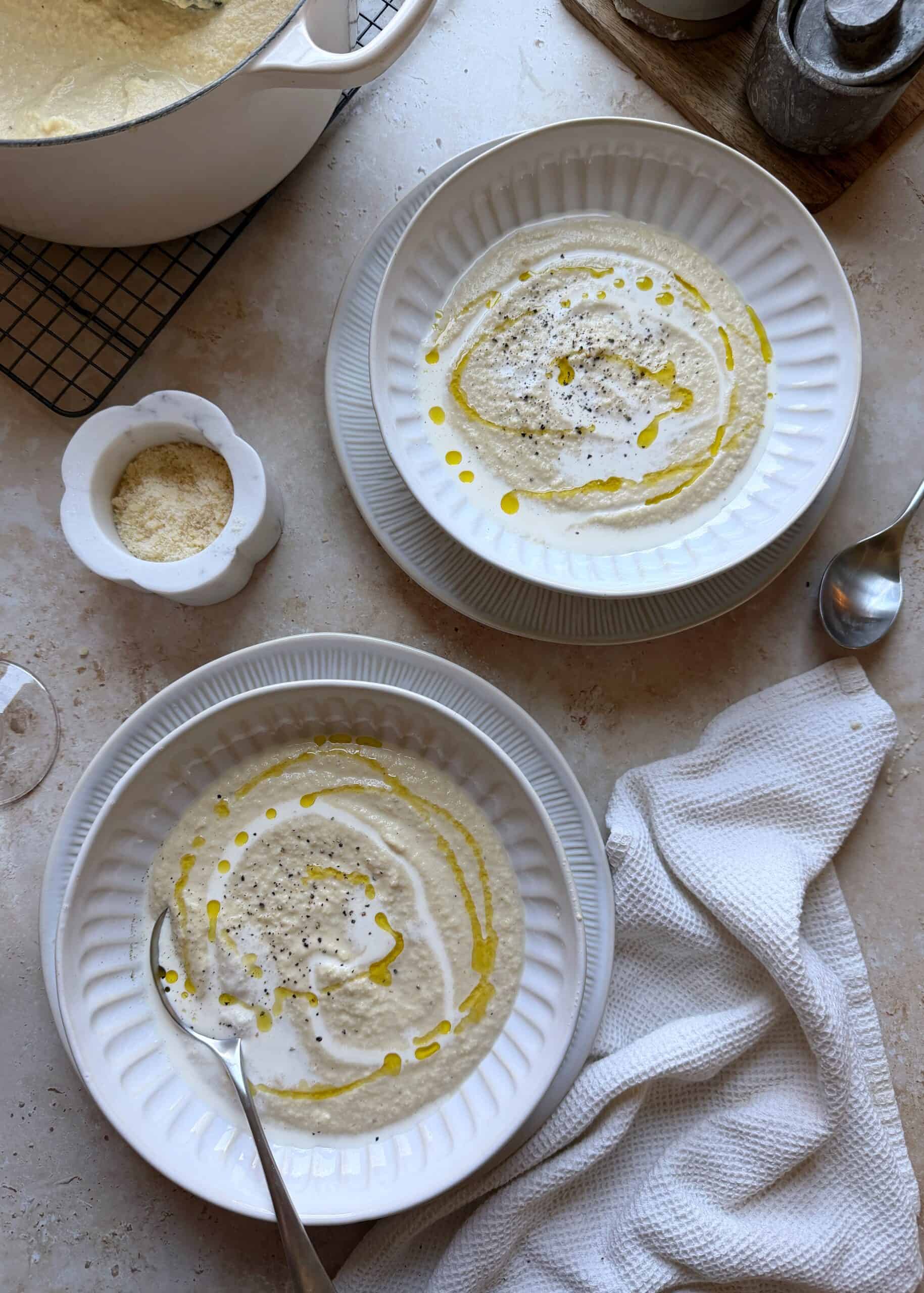 two bowls of roasted cauliflower soup with olive oil and black pepper