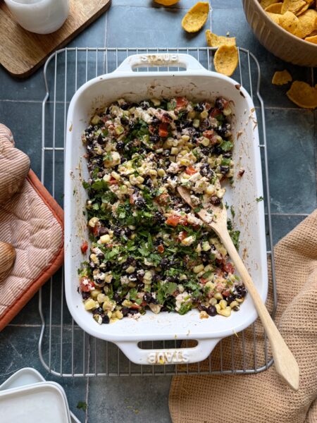 mixed baked black bean corn and feta dip topped with fresh cilantro and served with corn chips