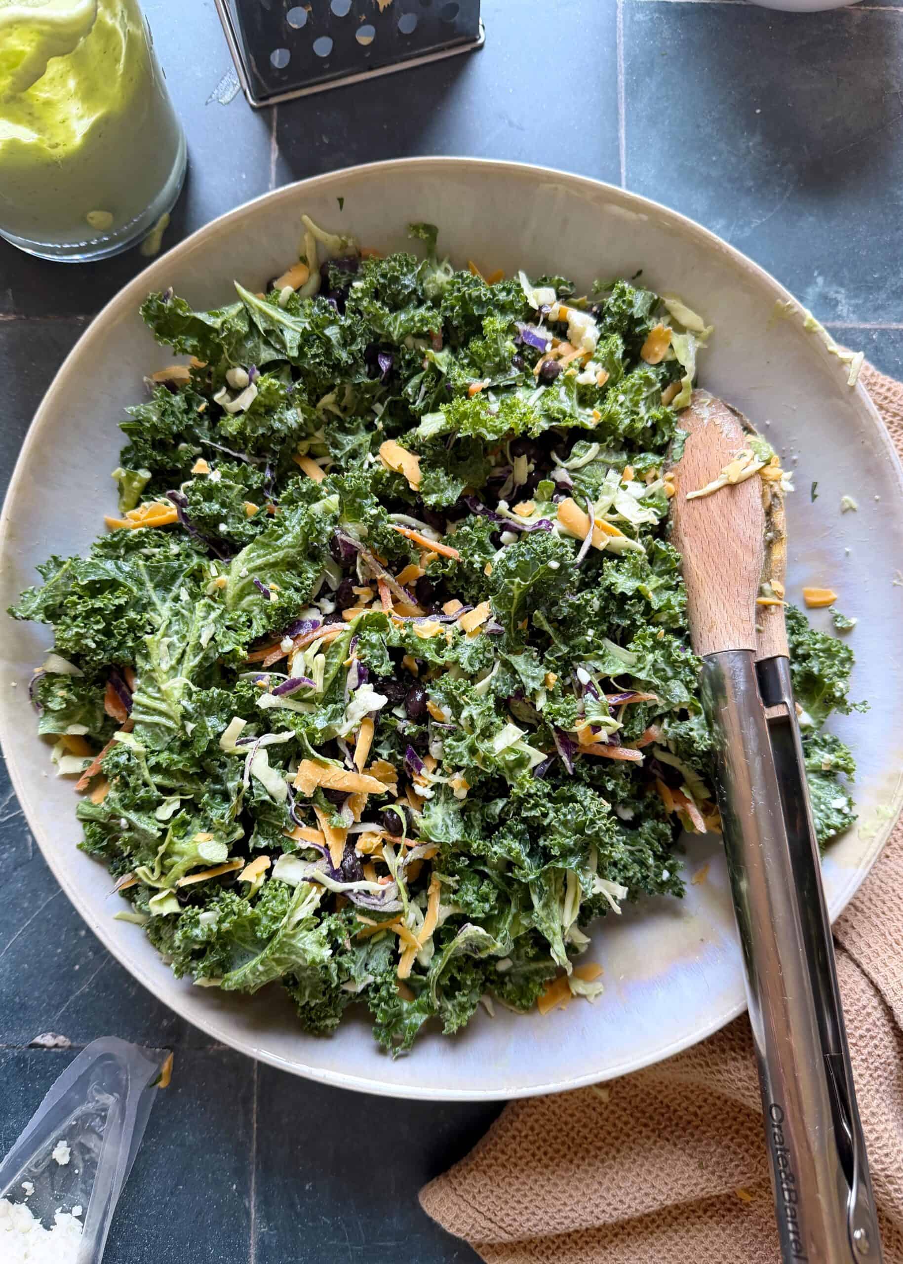turkey taco salad base tossed in avocado greek yogurt dressing with tongs on the side