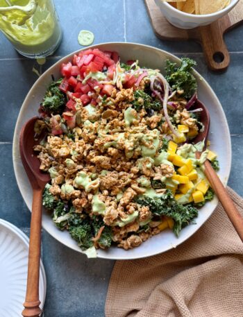 turkey taco salad with avocado greek yogurt dressing with wooden salad tongs in a white bowl