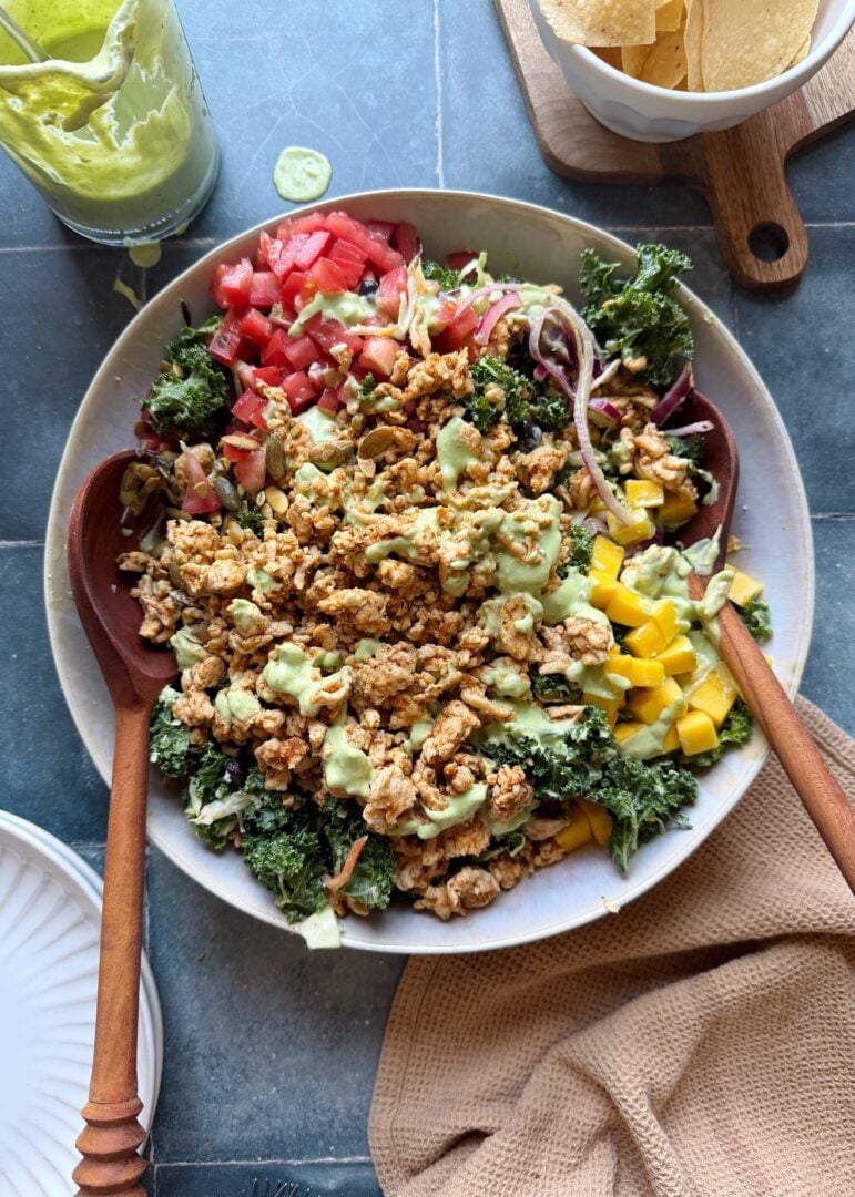 turkey taco salad with avocado greek yogurt dressing with wooden salad tongs in a white bowl