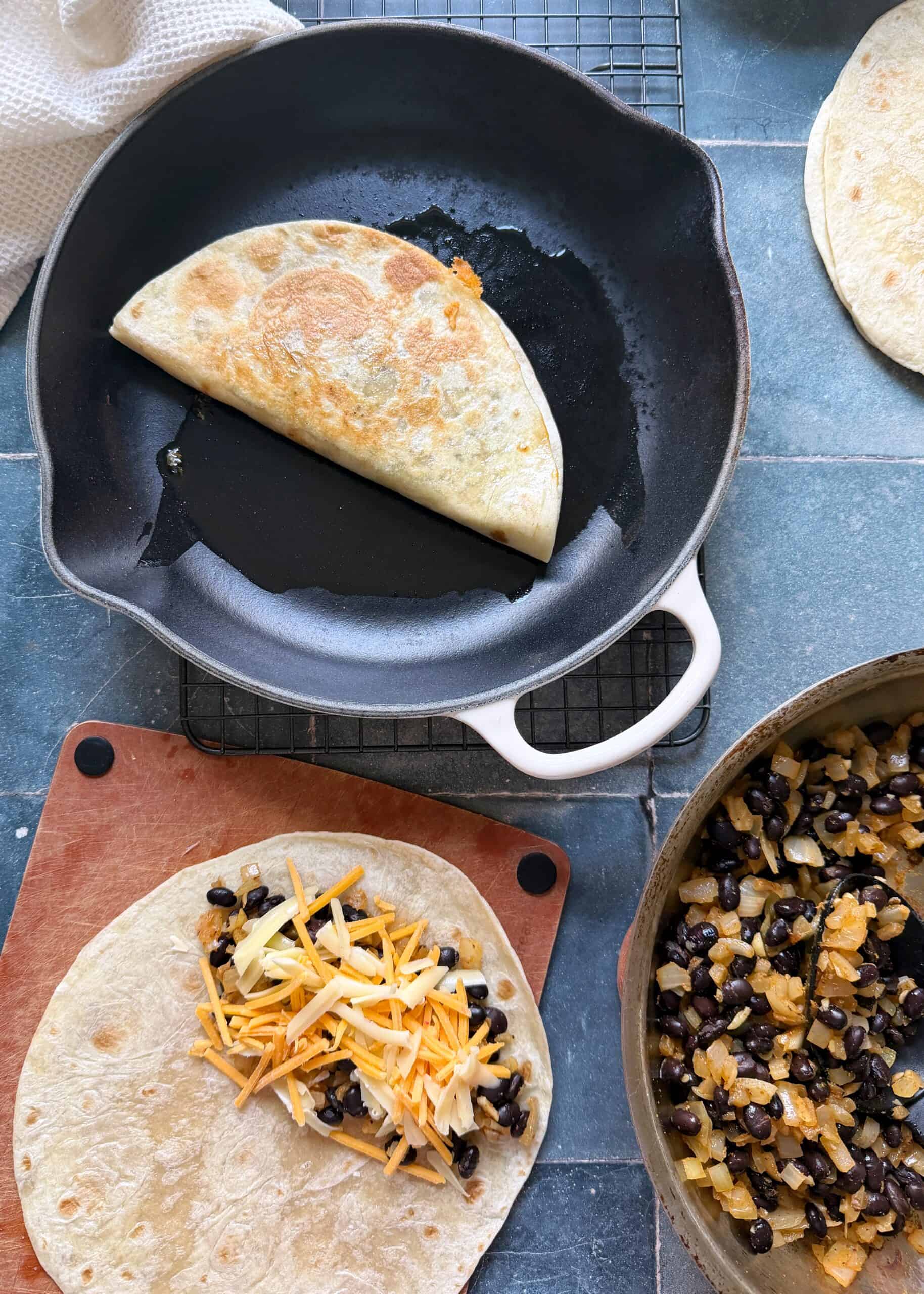 assembly and frying cheesy black bean quesadillas in a cast iron skillet