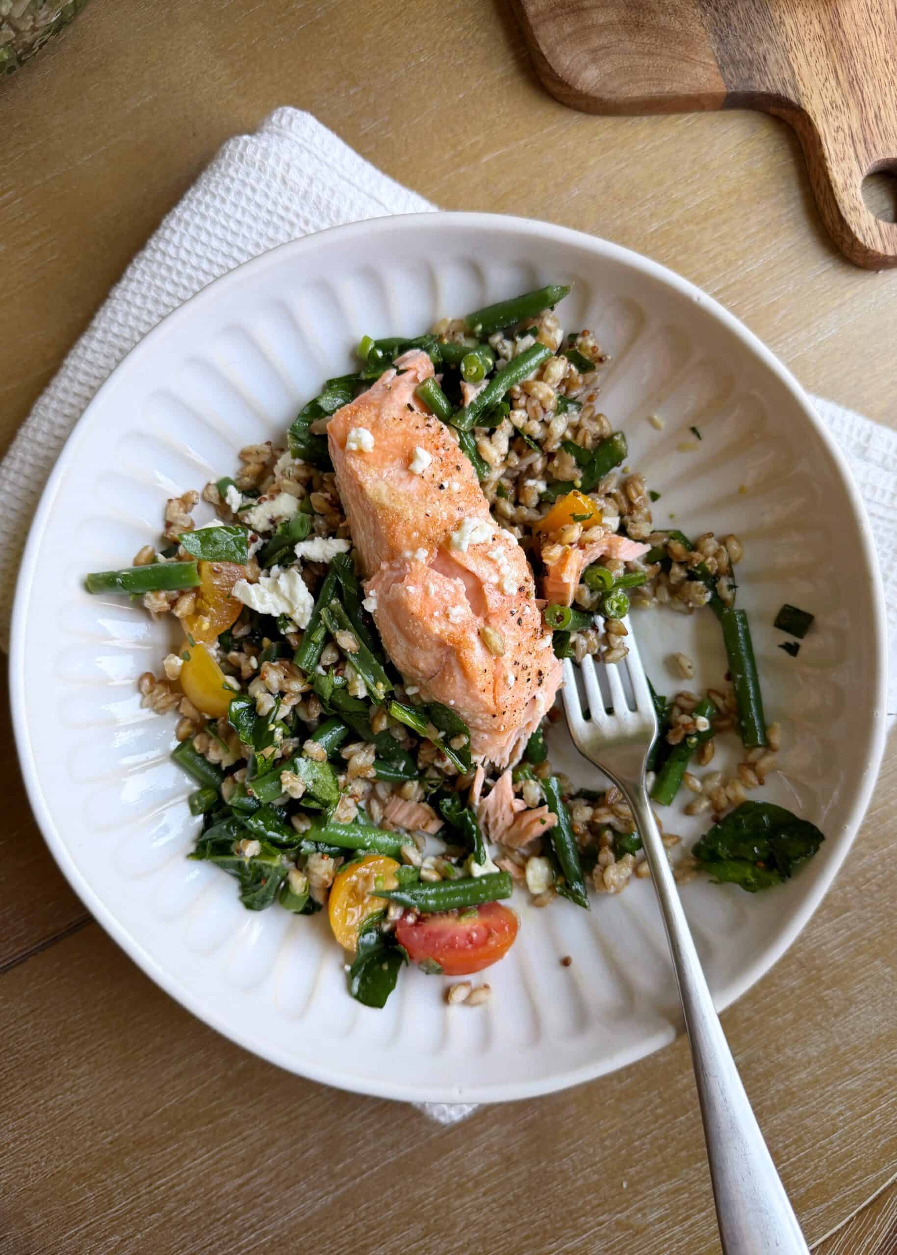 bowl of salmon with green bean farro salad with a silver fork