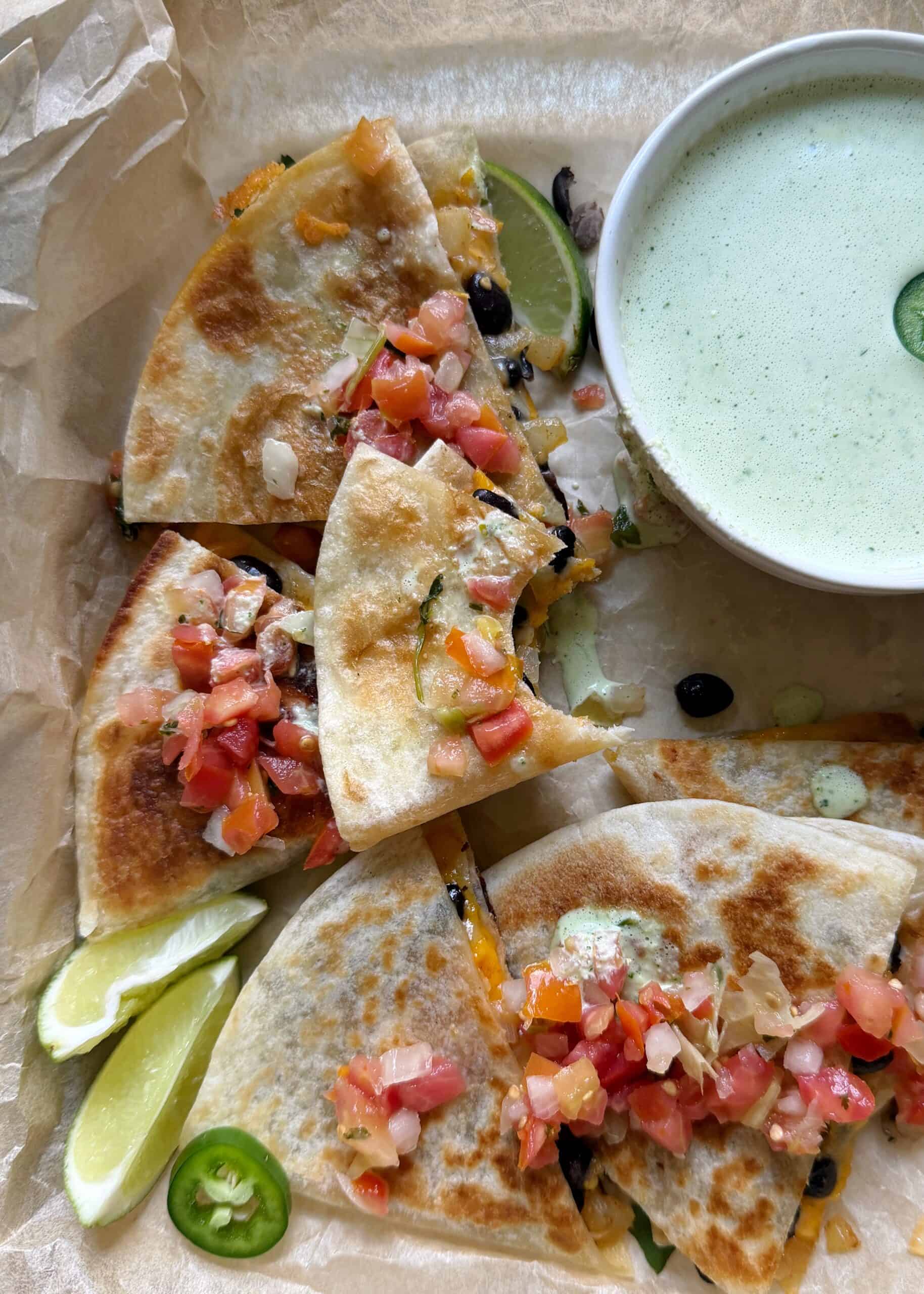 cheesy black bean quesadillas with jalapeno cilantro sauce on the side and pico de gallo garnish