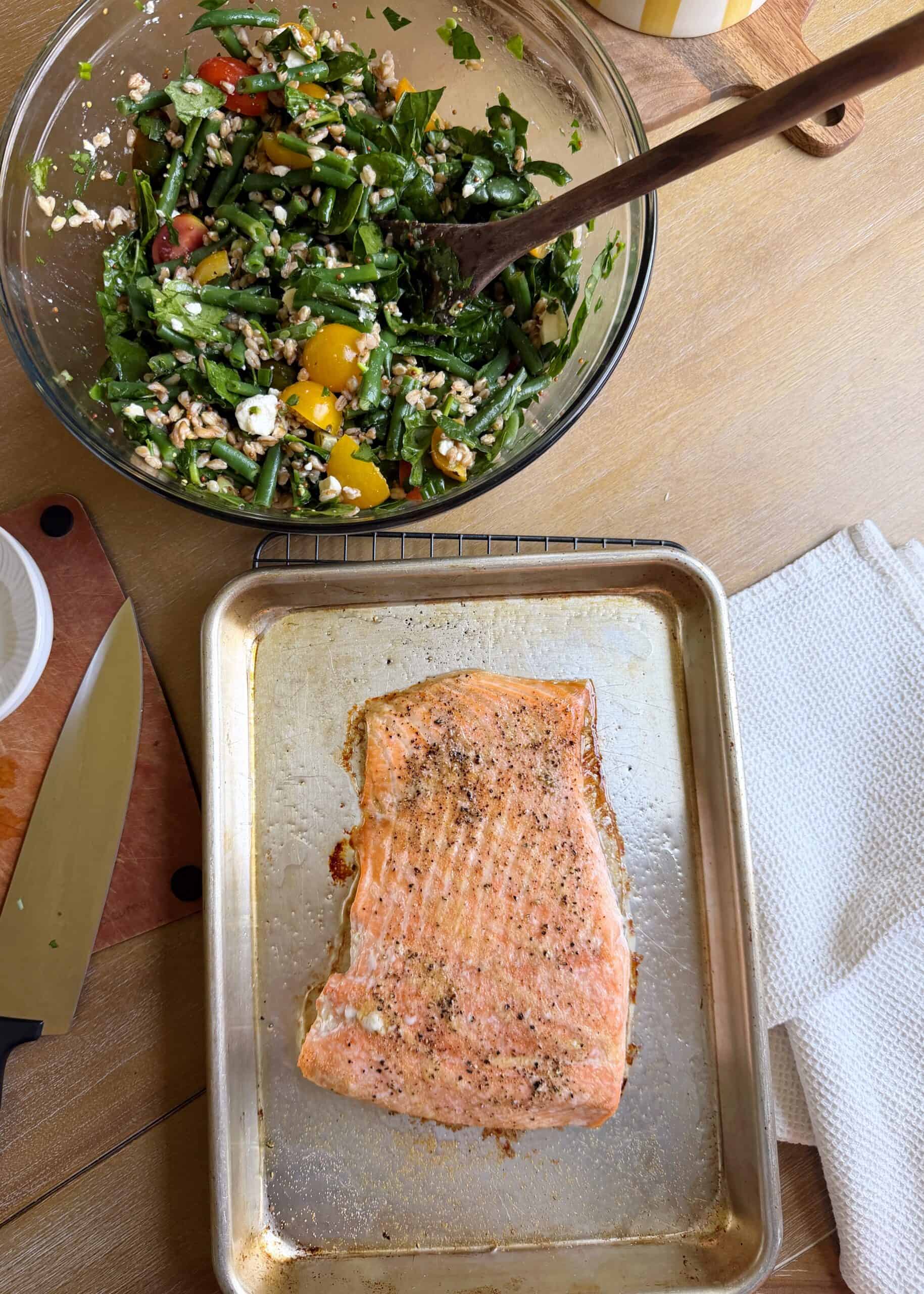 sheet pan of roasted salmon with bowl of green bean farro salad on the side